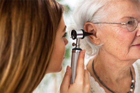 Doctor examining patient ear with otoscope