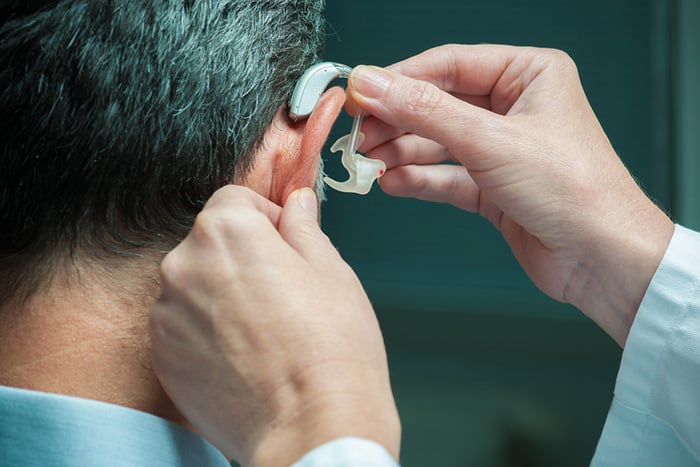Doctor inserting hearing aid