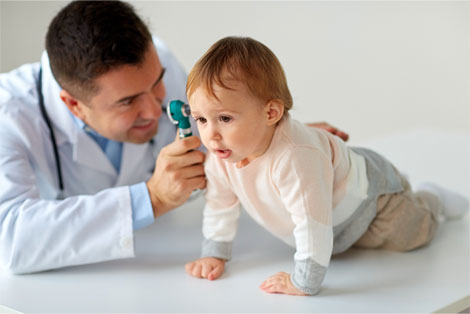 Pediatrician holding otoscope to examine baby