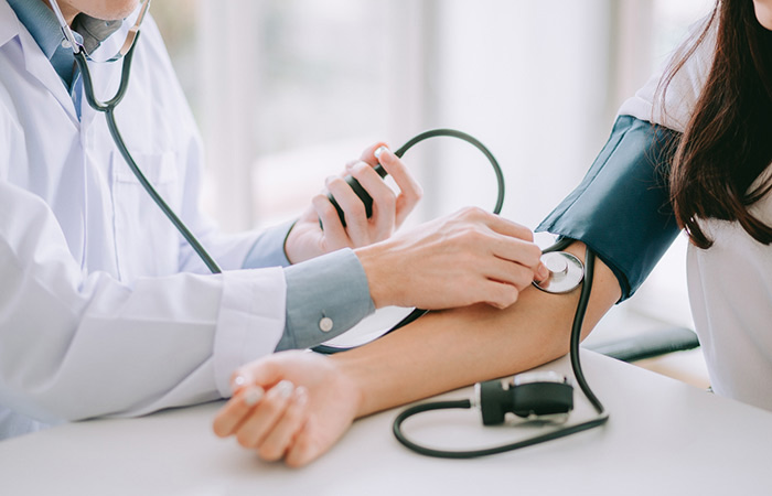 Doctor monitoring patient blood pressure with stethoscope and blood pressure cuff