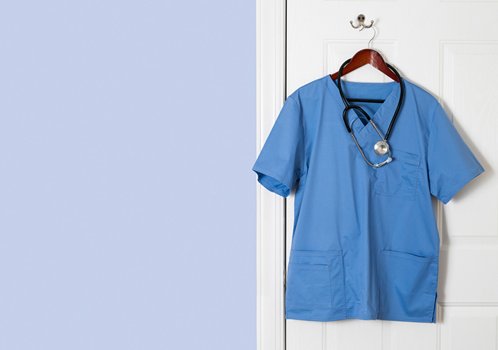 Mens blue scrub top hanging on door with stethoscope