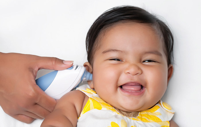 Women reads baby temperature using electronic ear thermometer