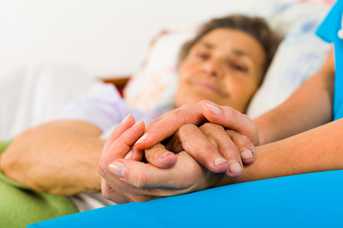 Caregiver holding elderly patient hand