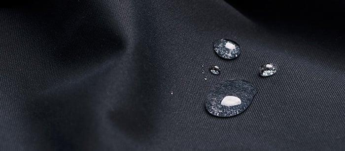 Close up of water drops on black waterproof fabric