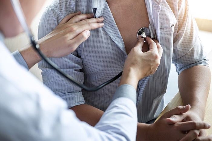 Doctor uses stethoscope to listen to patient chest sounds