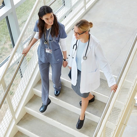 Doctor and nurse walk down stairs wearing Danskos