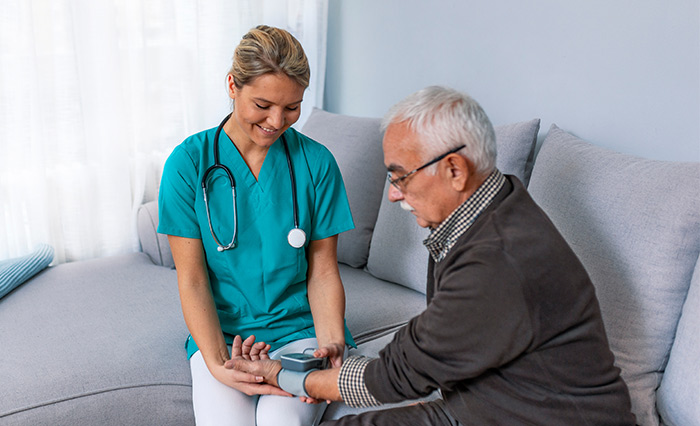 Female home health aide checking on a male senior patient at his home