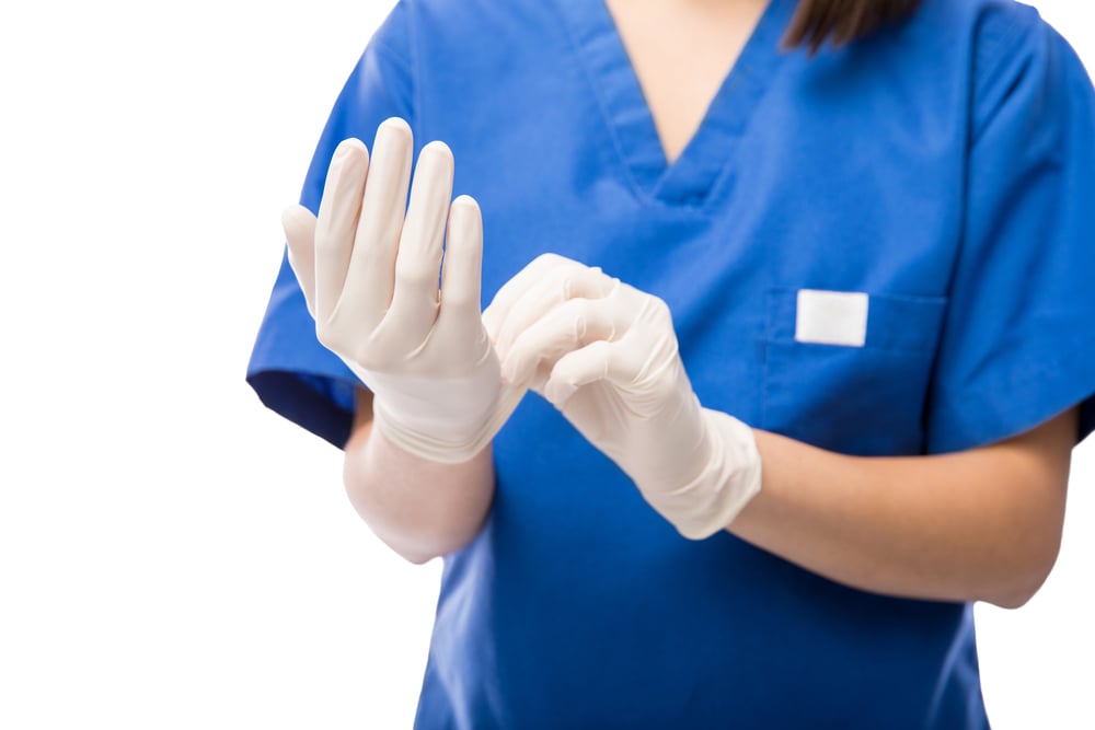 Female nurse putting on exam gloves