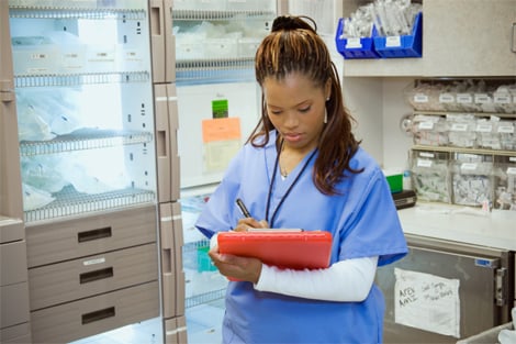 Female nurse taking notes on clipboard in medical supply room