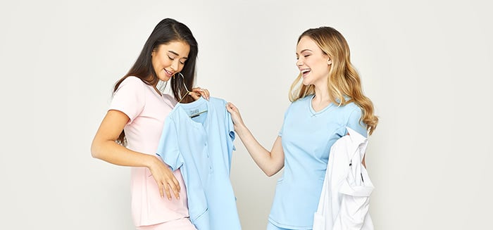 Two female nurses trying on colorful scrubs