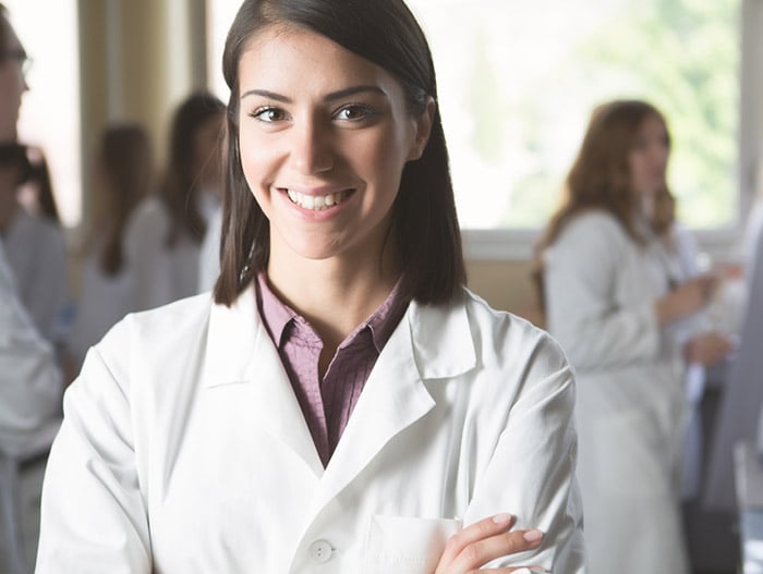 Female medical student wears white coat during ceremony