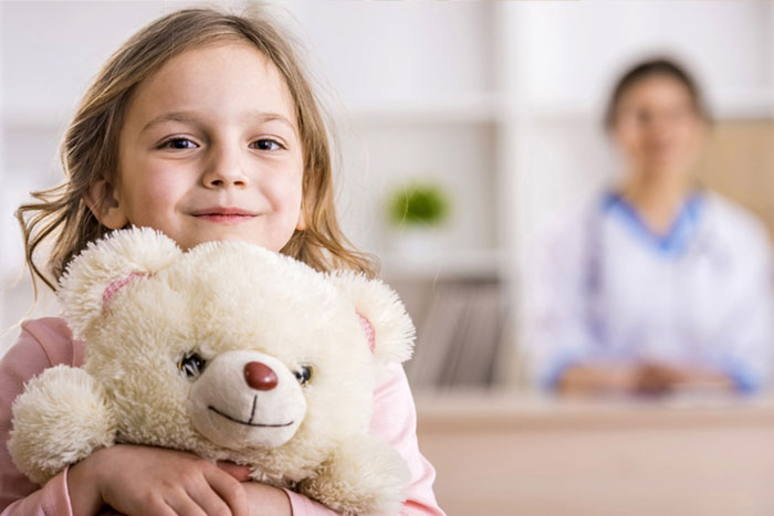 Girl hugs bear in doctors waiting room