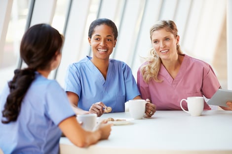 Group of female nurses talking together at table