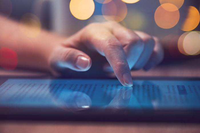 Woman’s hand scrolling through news stories on tablet