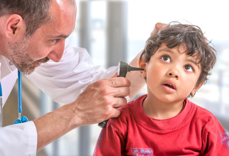 Male doctor using an otoscope to examine a young child’s ear