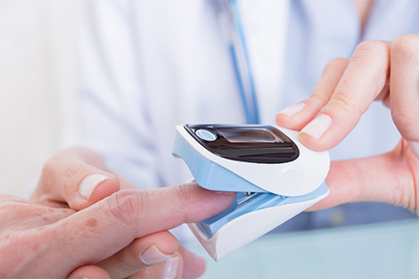 Nurse clipping a pulse oximeter to a patient’s fingertip