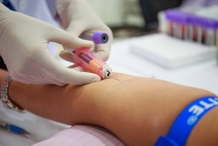 nurse taking blood sample from patient arm