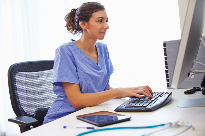 female nurse typing on office computer