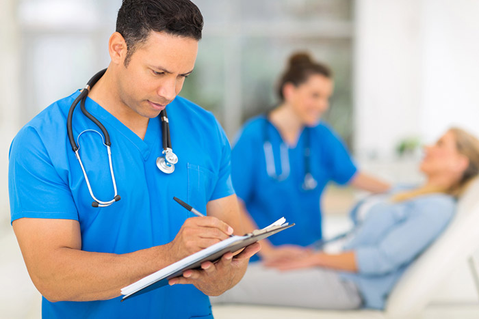 medical professional writing on a clipboard with patient in background