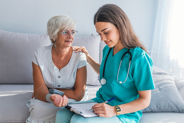 nursing assistant sitting with elderly patient