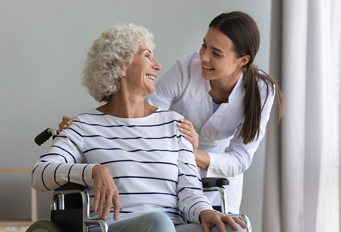 nursing assistant helping senior patient in wheelchair