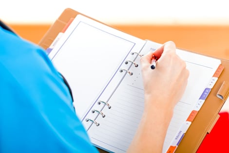 Nursing student writing notes in notebook