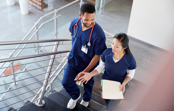 two physician assistants talking on stairs