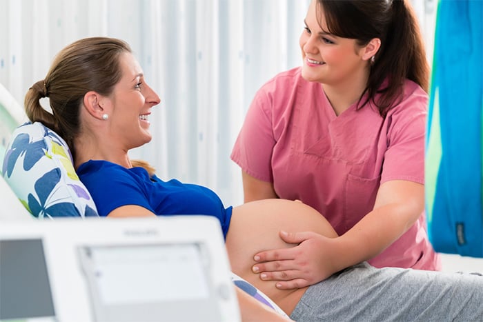 nurse with pregnant woman in delivery room
