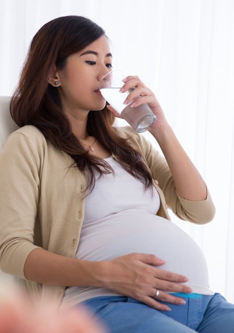 Pregnant woman sitting in a chair and drinking water