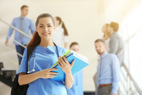 Smiling female nursing student holding a backpack and books