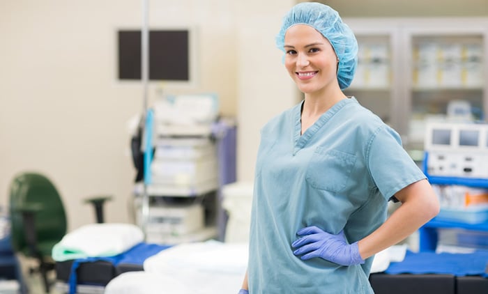 Smiling surgeon wears bouffant scrub cap in operating room