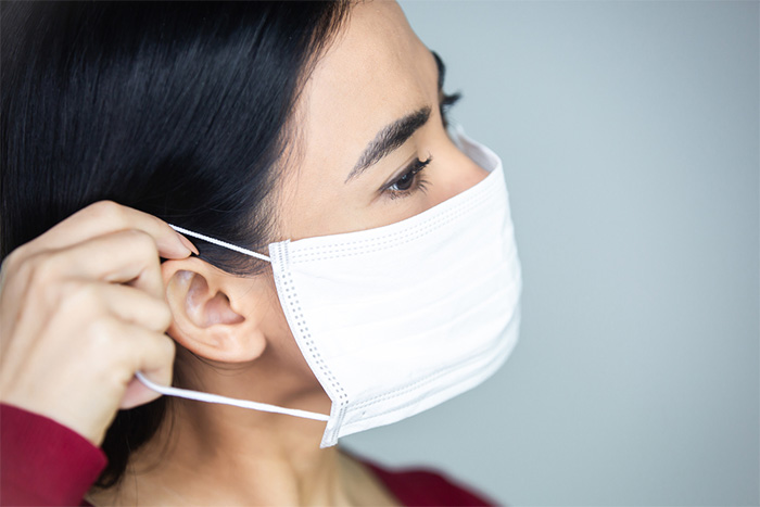 woman putting on protective face mask