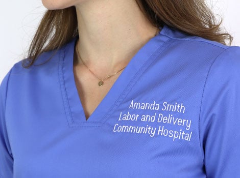 Woman wearing custom blue scrubs with white embroidery